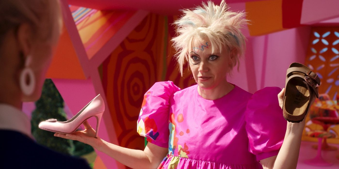 Weird Barbie (Kate McKinnon) holding two different shoes in either hand in the Barbie movie. 