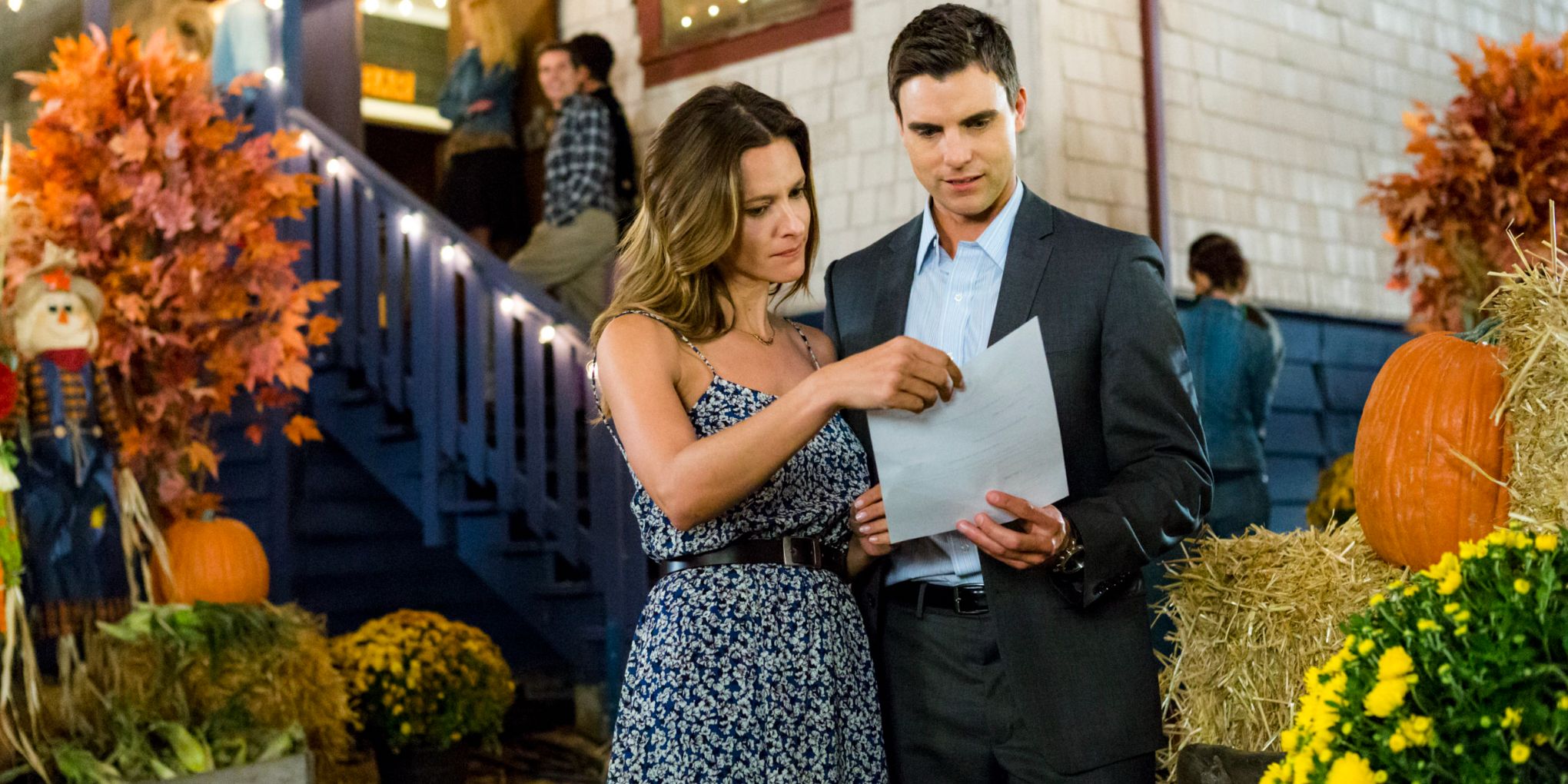 Jill Wagner and Colin Egglesfield examining a piece of paper at a fall festival in Autumn Dreams