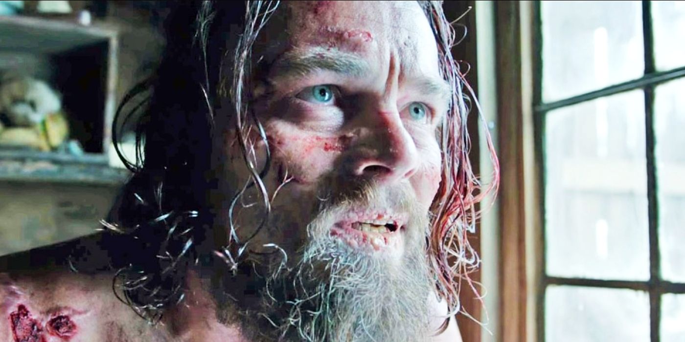 Hugh Glass (Leonardo DiCaprio) covered in injuries looks out a window in The Revenant.