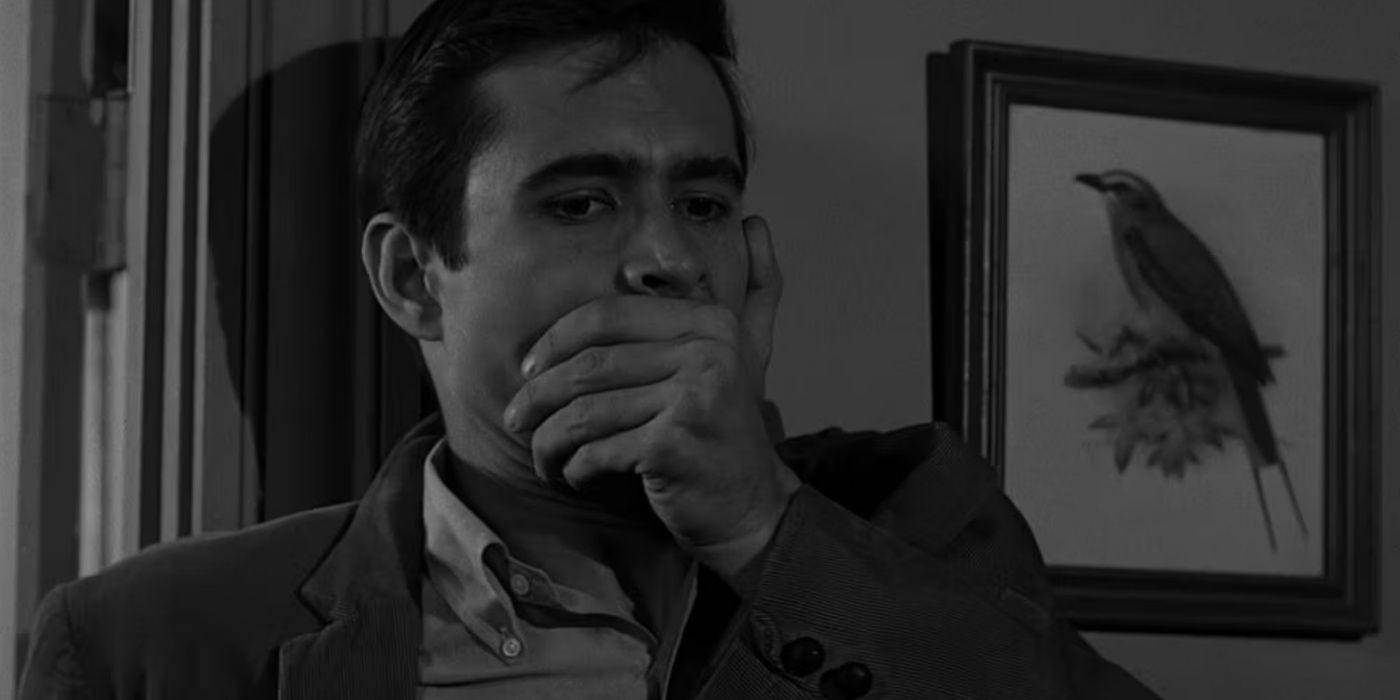 Norman Bates with his hand over his mouth in Psycho.
