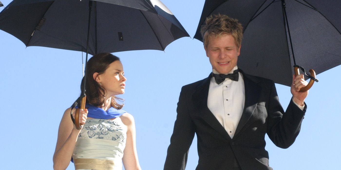 Rory Gilmore (Alexis Bledel) and Logan Huntzberger (Matt Czuchry) standing together in formal clothing holding umbrellas in Gilmore Girls