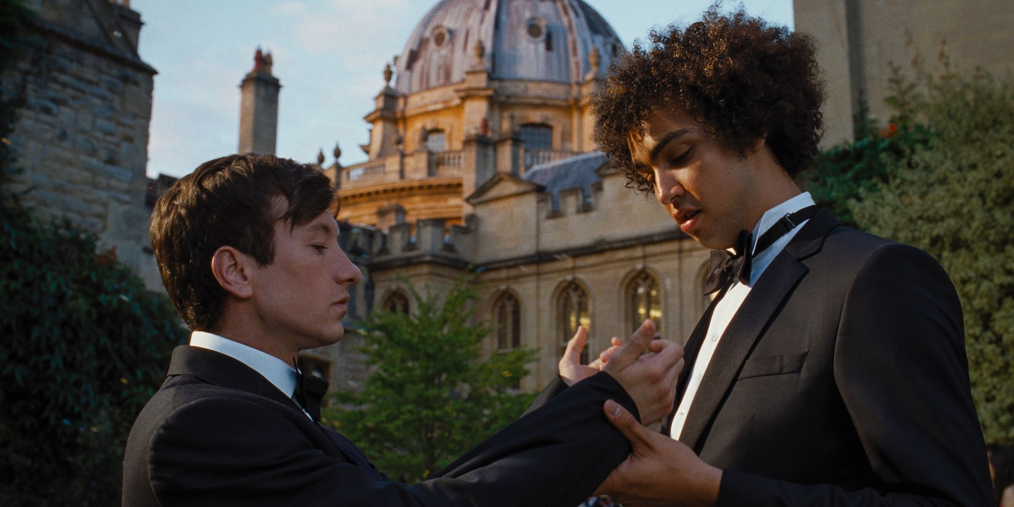 Oliver Quick (Barry Keoghan) showing the sleeves of his tuxedo to Farleigh Start (Archie Madekwe) in Saltburn.