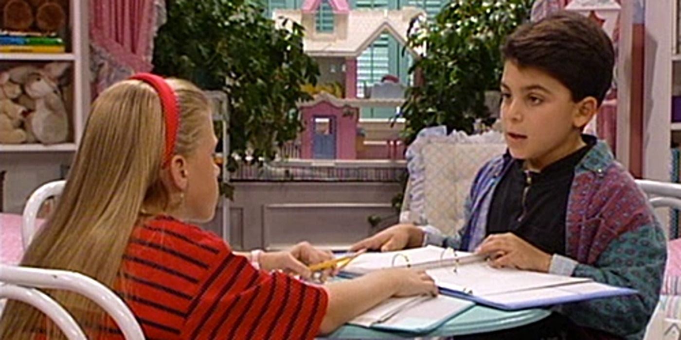 Stephanie and her friend sitting at a table with papers in front of them in Full House