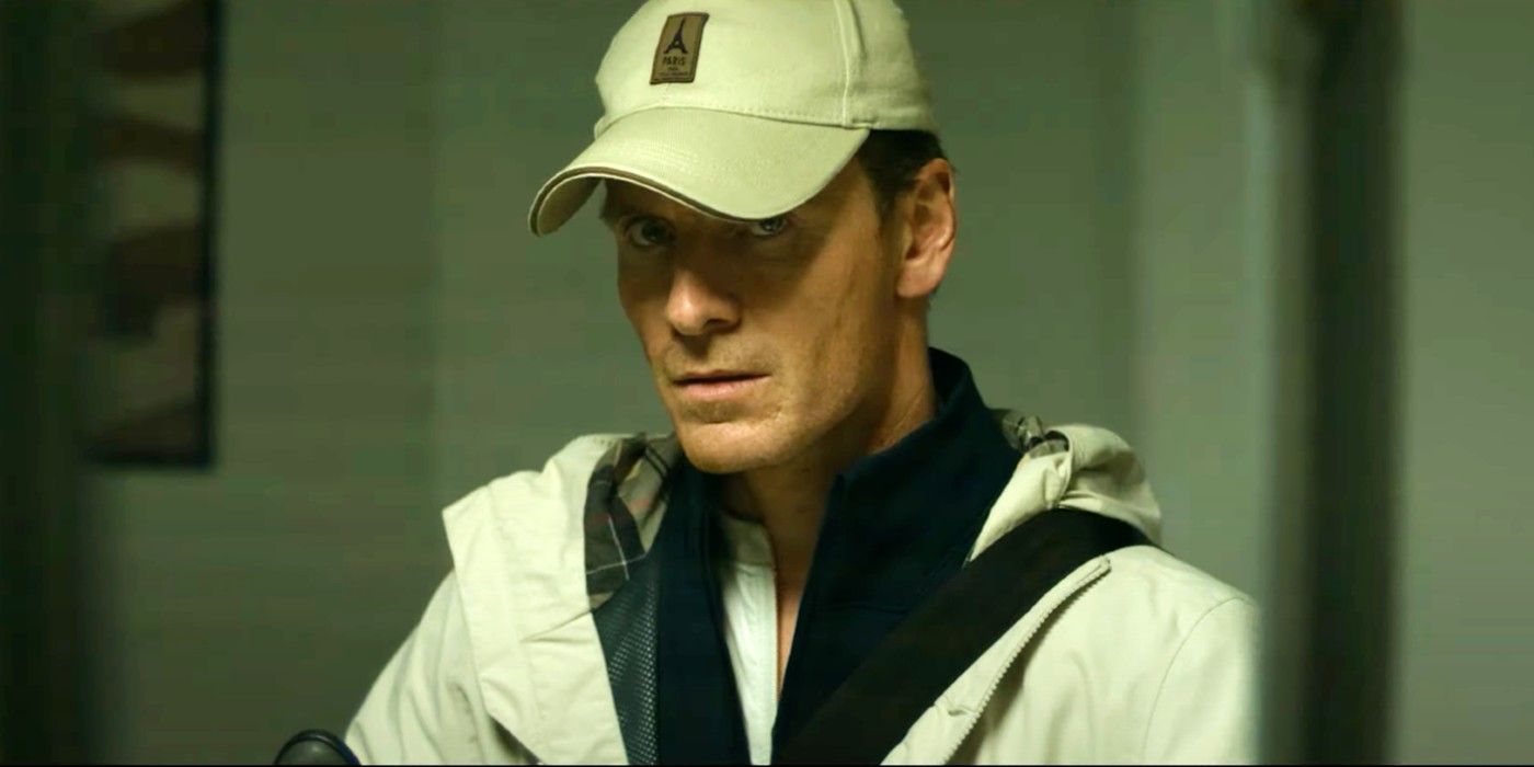 Michael Fassbender como The Killer, con una gorra y mirando a la cámara en The Killer
