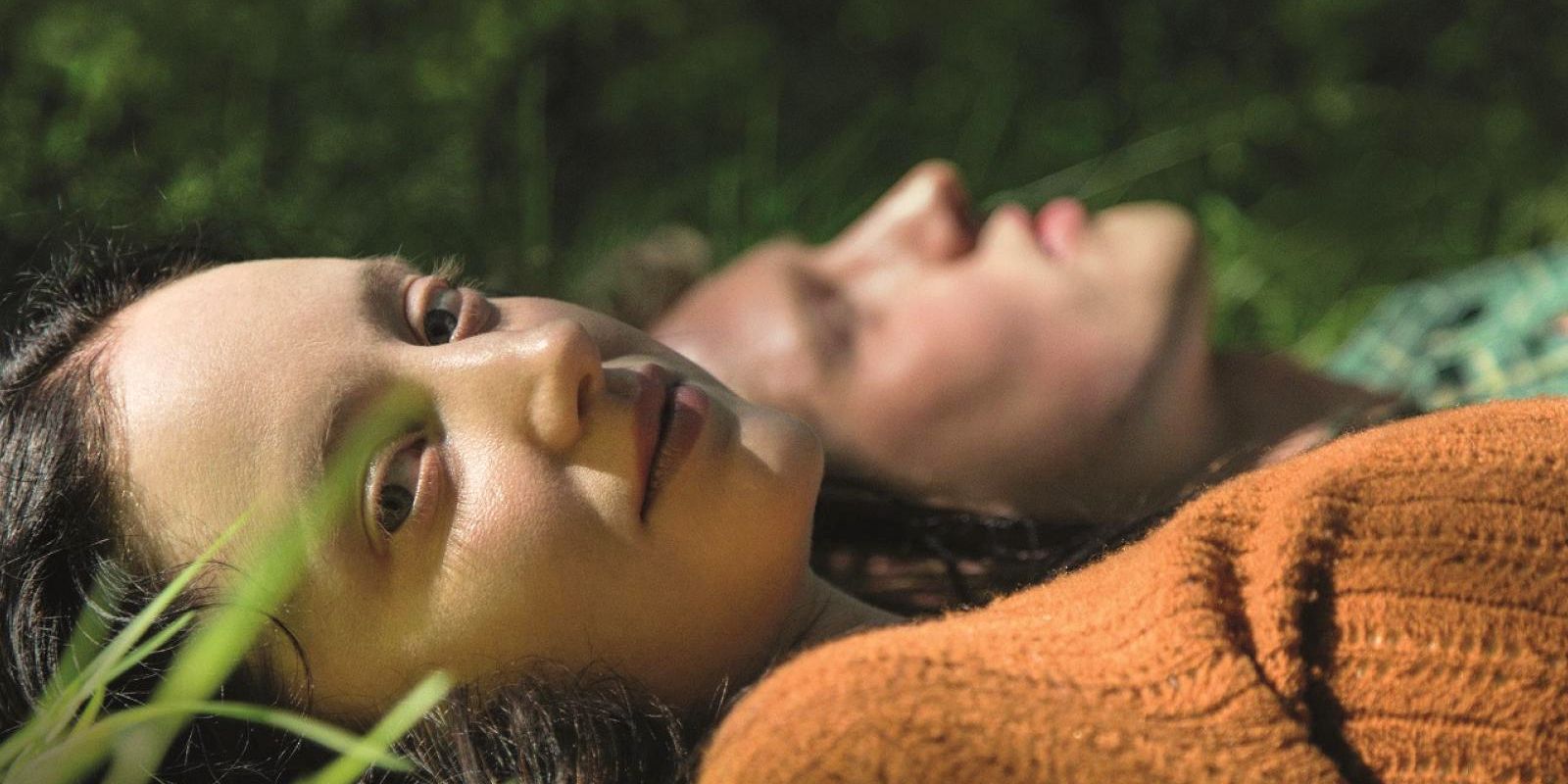 Aislin lays in the grass looking at the camera with her delinquent boyfriend next to her.