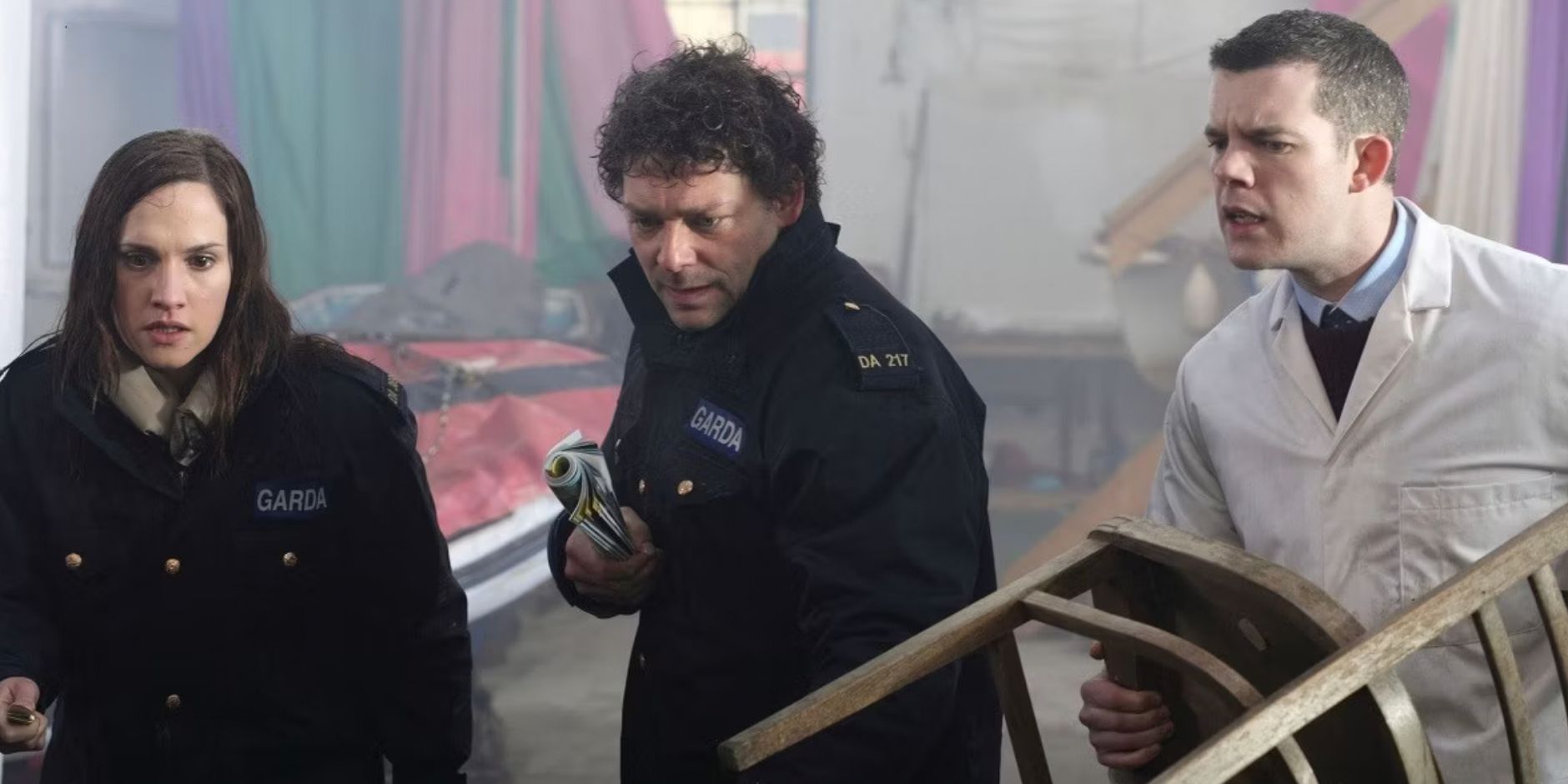 Ruth Bradley's Lisa, Richard Coyle's Ciaran, and Russell Tovey's Adam look at something off screen and prepare to fight with found objects in Grabbers