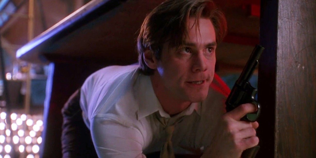 Jim Carrey hiding under a desk with a gun in The Mask