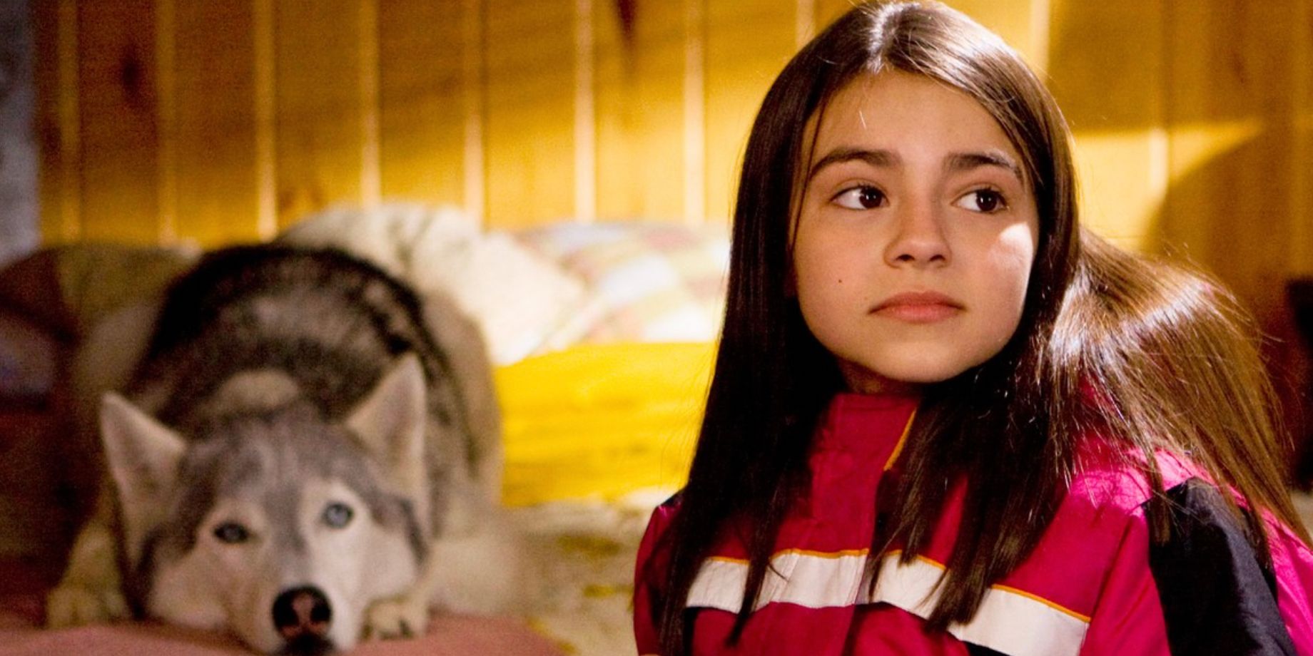 A young girl looks at something off screen while a dog lays down behind her in Call of the Wild
