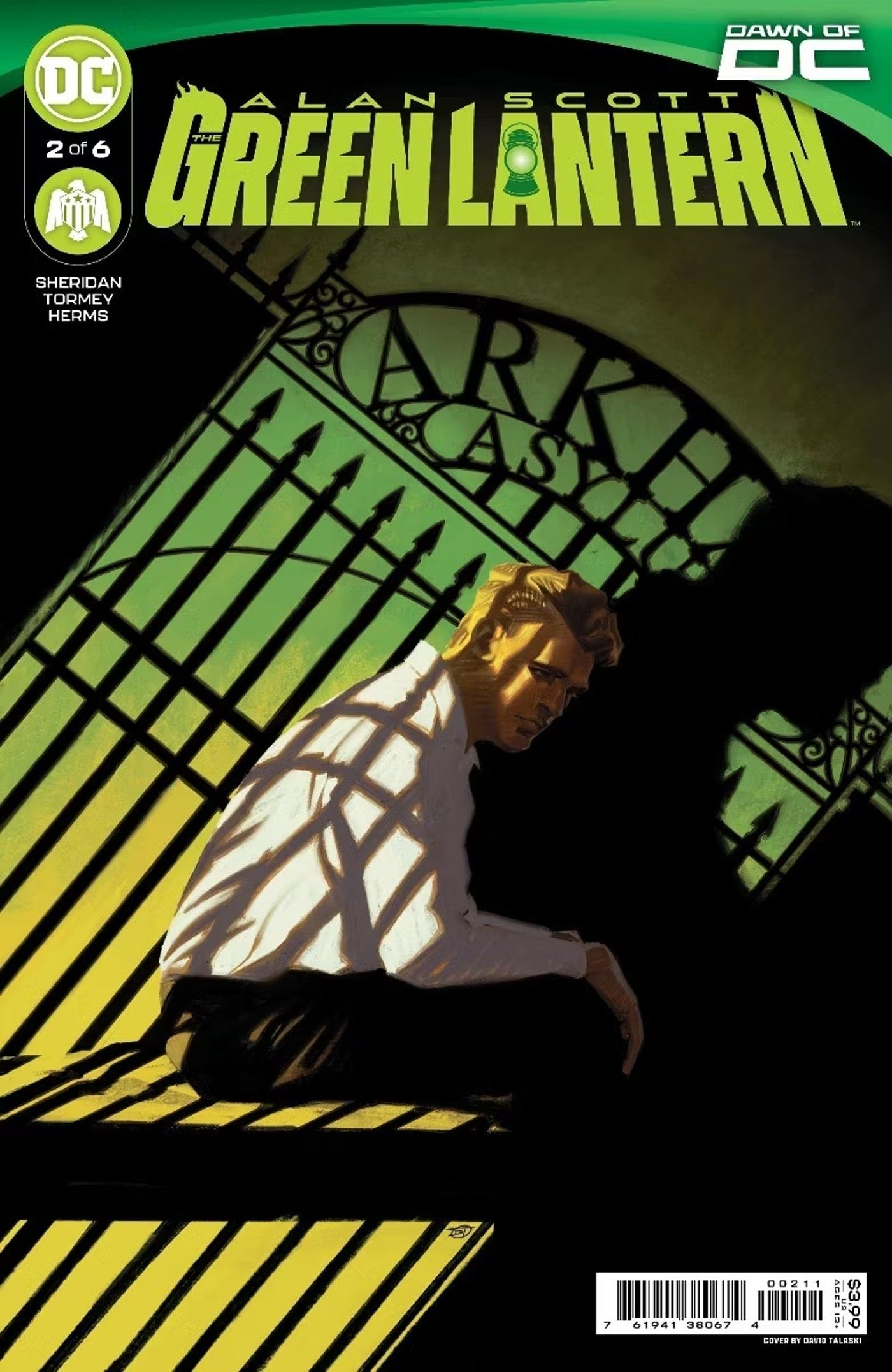 Alan Scott The Green Lantern 2 Main Cover: a blond man sits in the shadow of Arkham Asylum&rsquo;s gates.