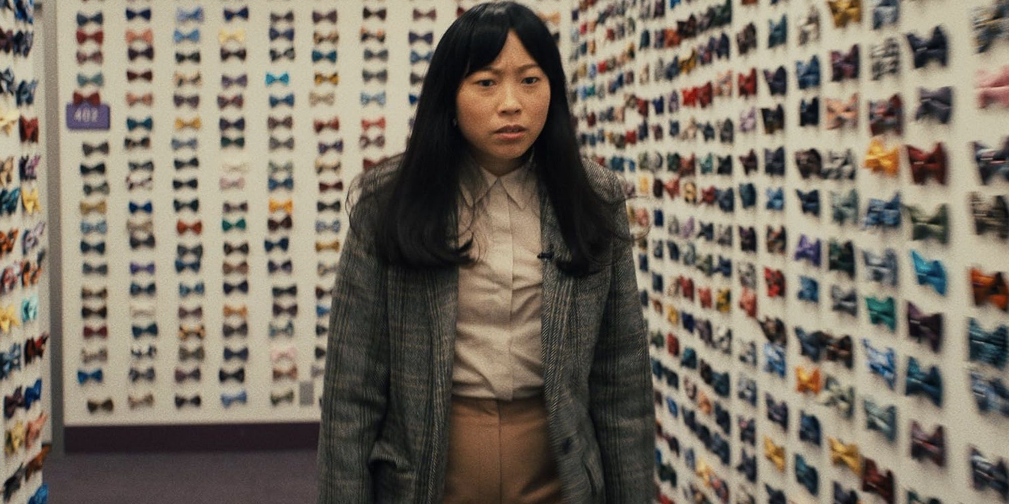 Awkwafina as Anne in a room full of bowties in Quiz Lady