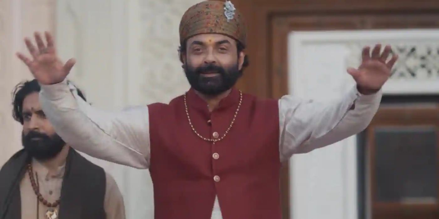 Baba with his hands raised, smiling in Aashram.