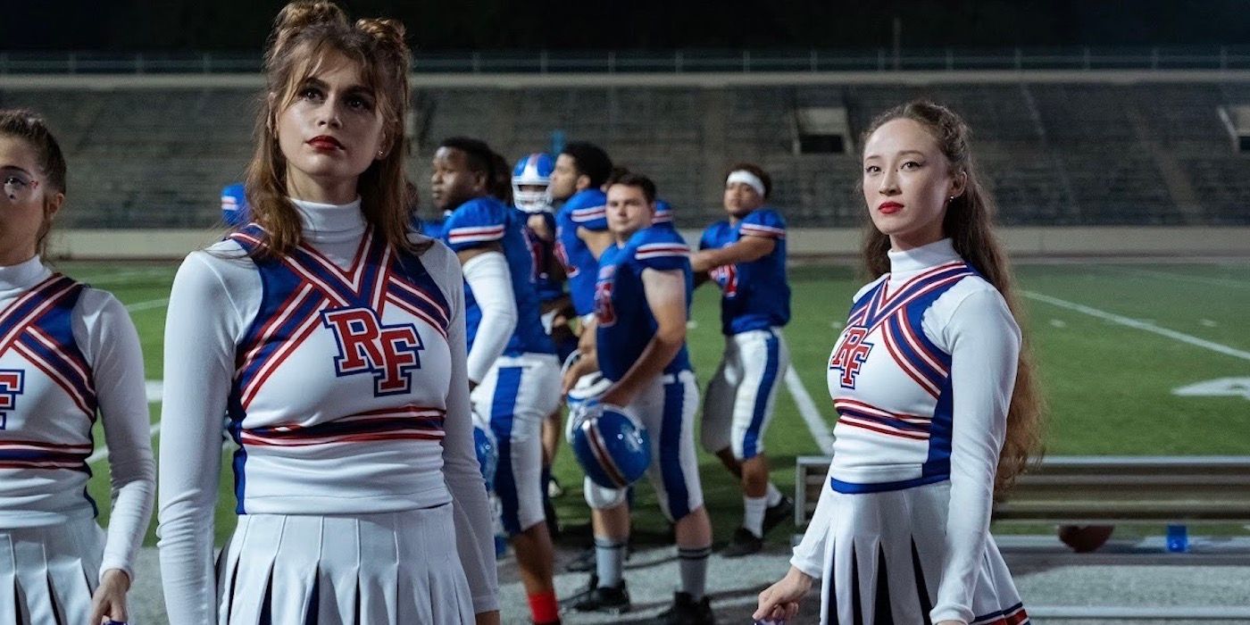 Brittany and Isabel in cheerleading uniforms on the field in Bottoms