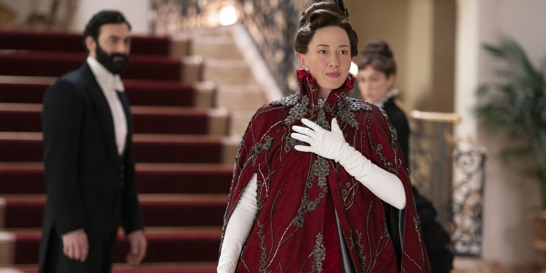 Carrie Coon as Bertha wearing an embroidered red cloak in The Gilded Age
