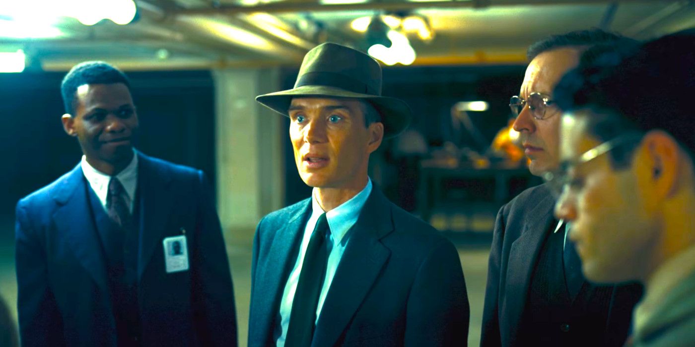 Cillian Murphy talking with wide-eyed intensity to a group of men in Oppenheimer