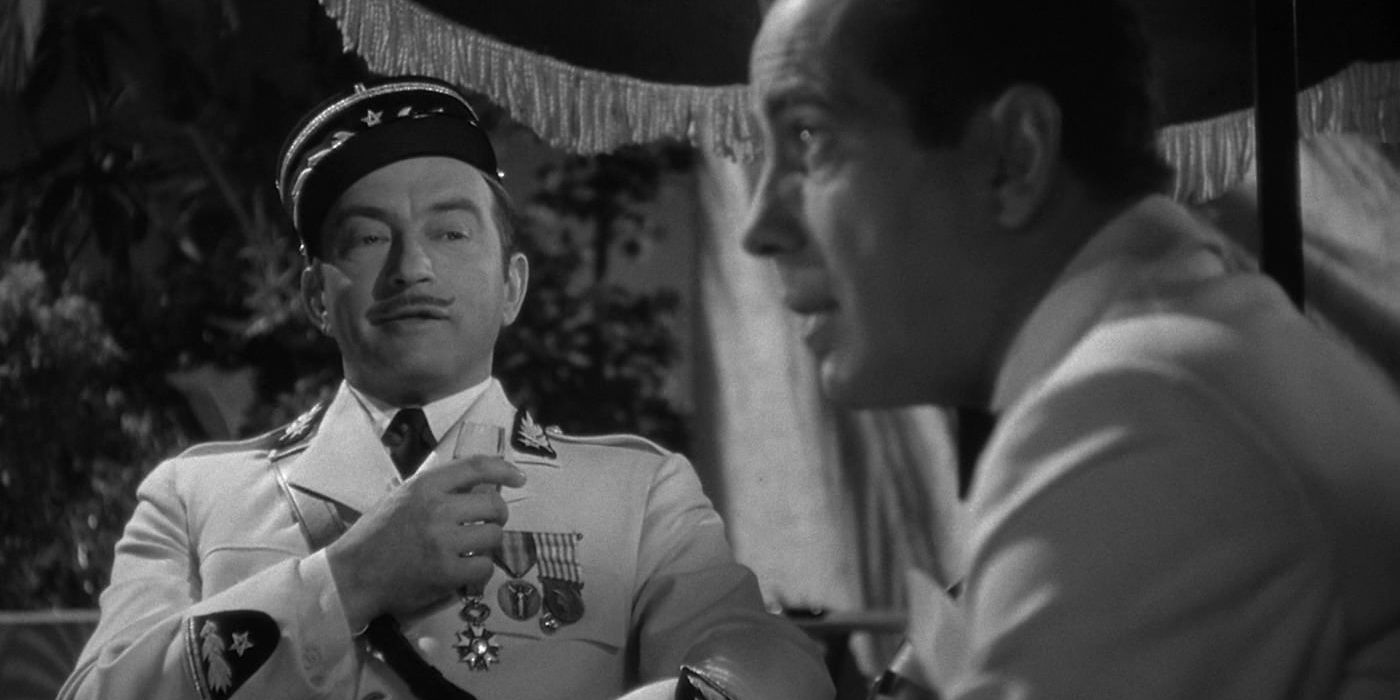 Claude Rains as Captain Louis Renault and Humphrey Bogart as Rick Blaine sitting in Casablanca together in Casablanca. 