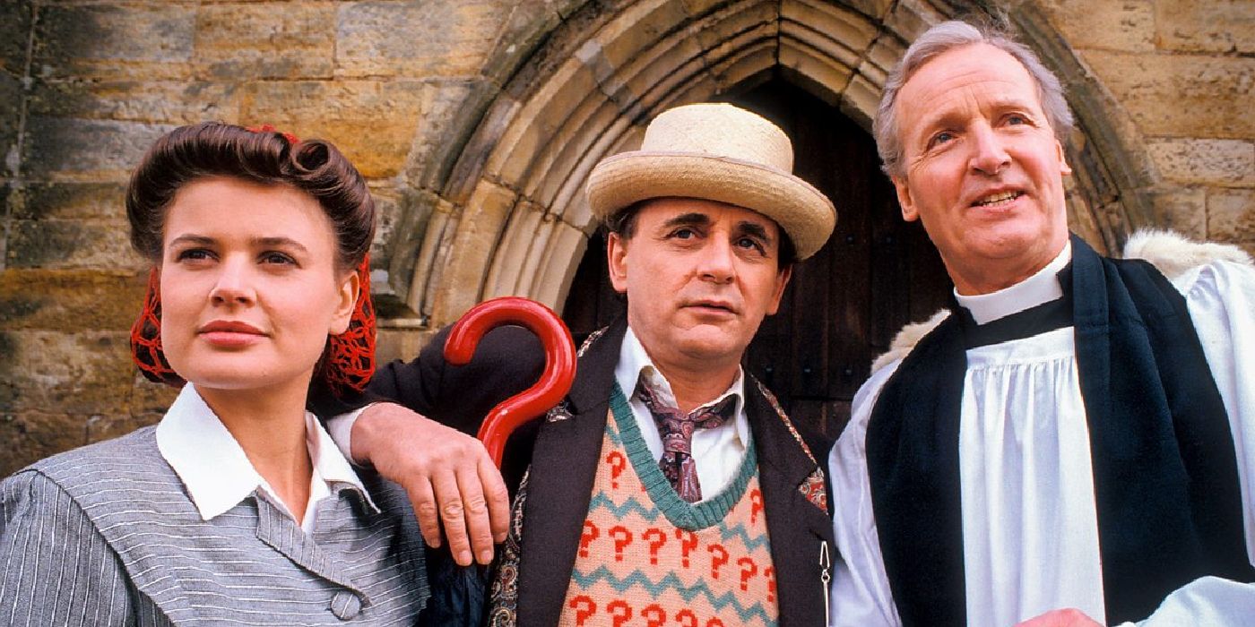 Sylvester McCoy standing between Ace and Rev. Wainwright in Doctor Who.