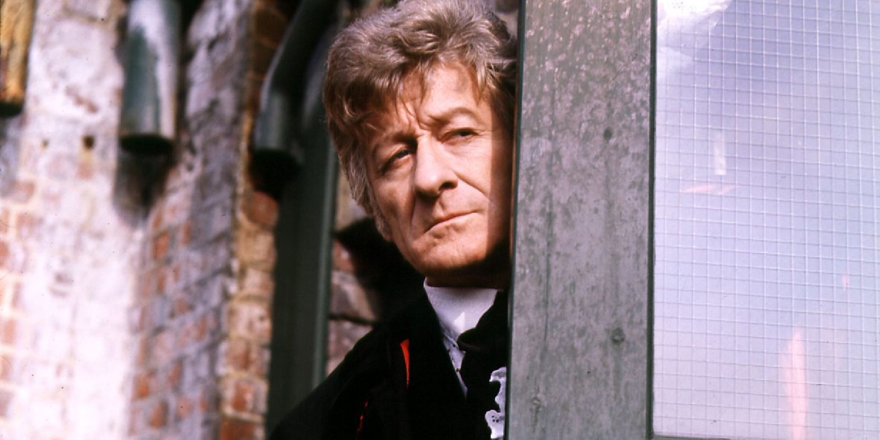 The Doctor peers round a door looking down a fire escape in Doctor Who's "Spearhead from Space"