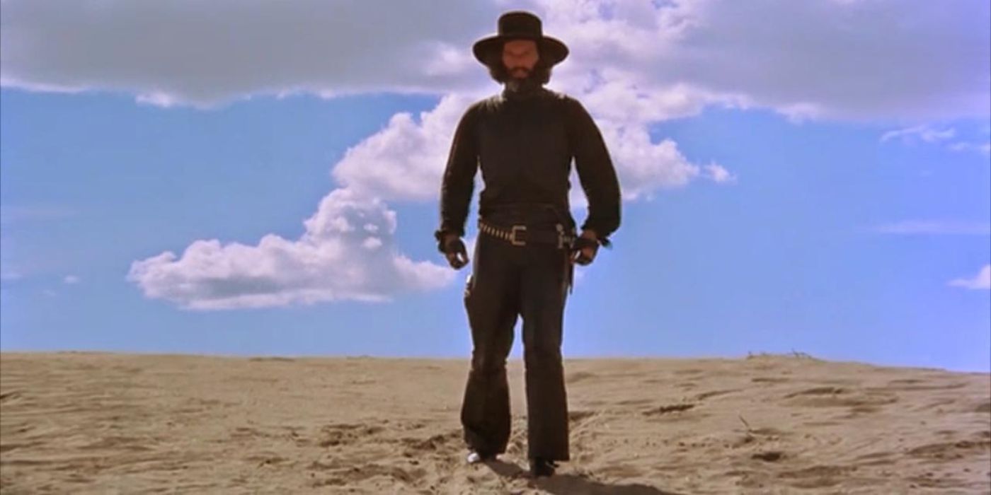The Gunslinger/El Topo reaches for his revolver while advancing through the desert on a hot day in El Topo