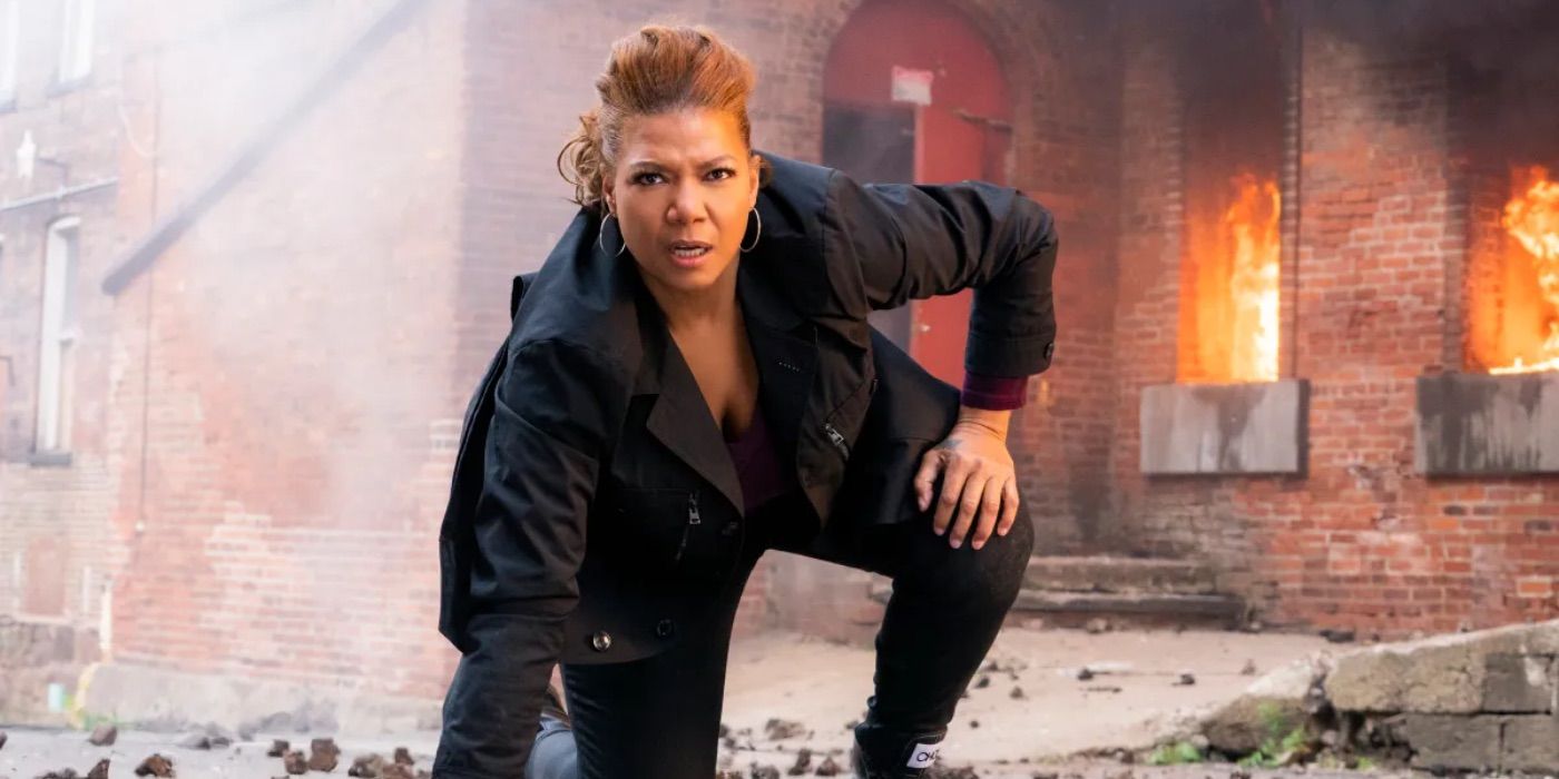 Queen Latifah as Robyn kneels near an explosion in The Equalizer