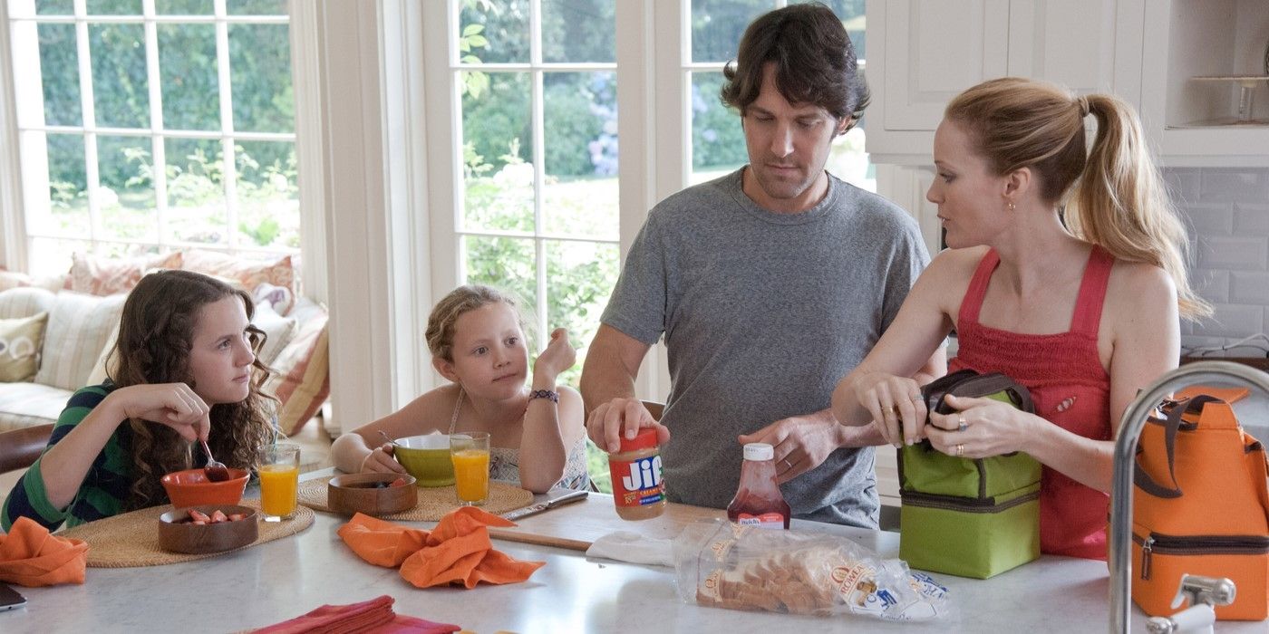 Maude and Iris Apatow eating breakfast while Debbie (Leslie Mann) and Pete (Paul Rudd) packs their lunch and Paul Rudd holds peanut butter in This Is 40