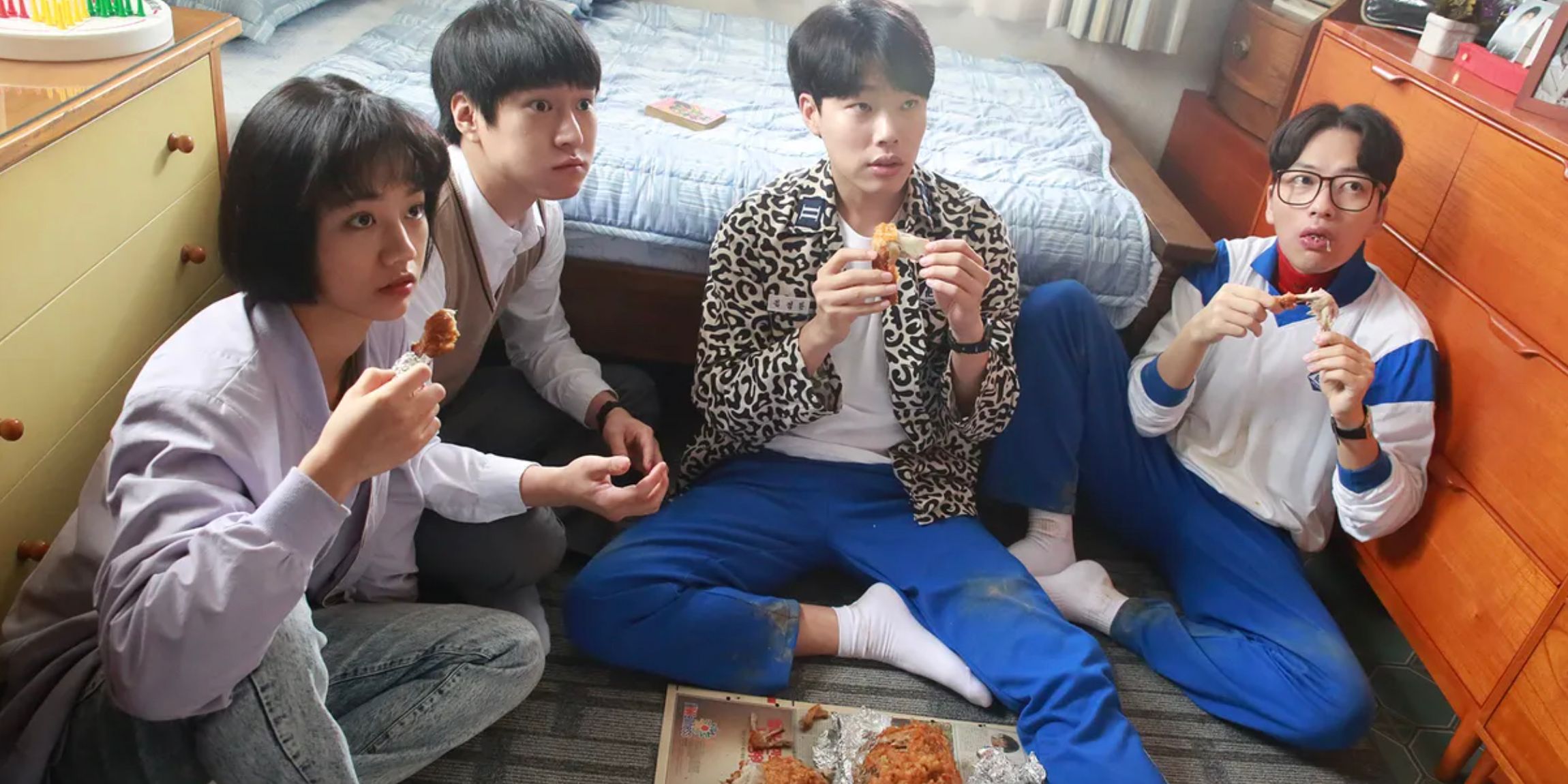 Four friends eating chicken on the floor of a bedroom in Reply 1988
