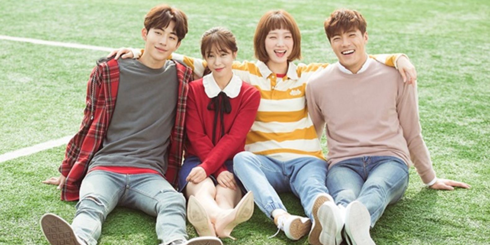 Four of the main cast of Weightlifting Fairy Kim Bok-joo sitting on the grass of a football field