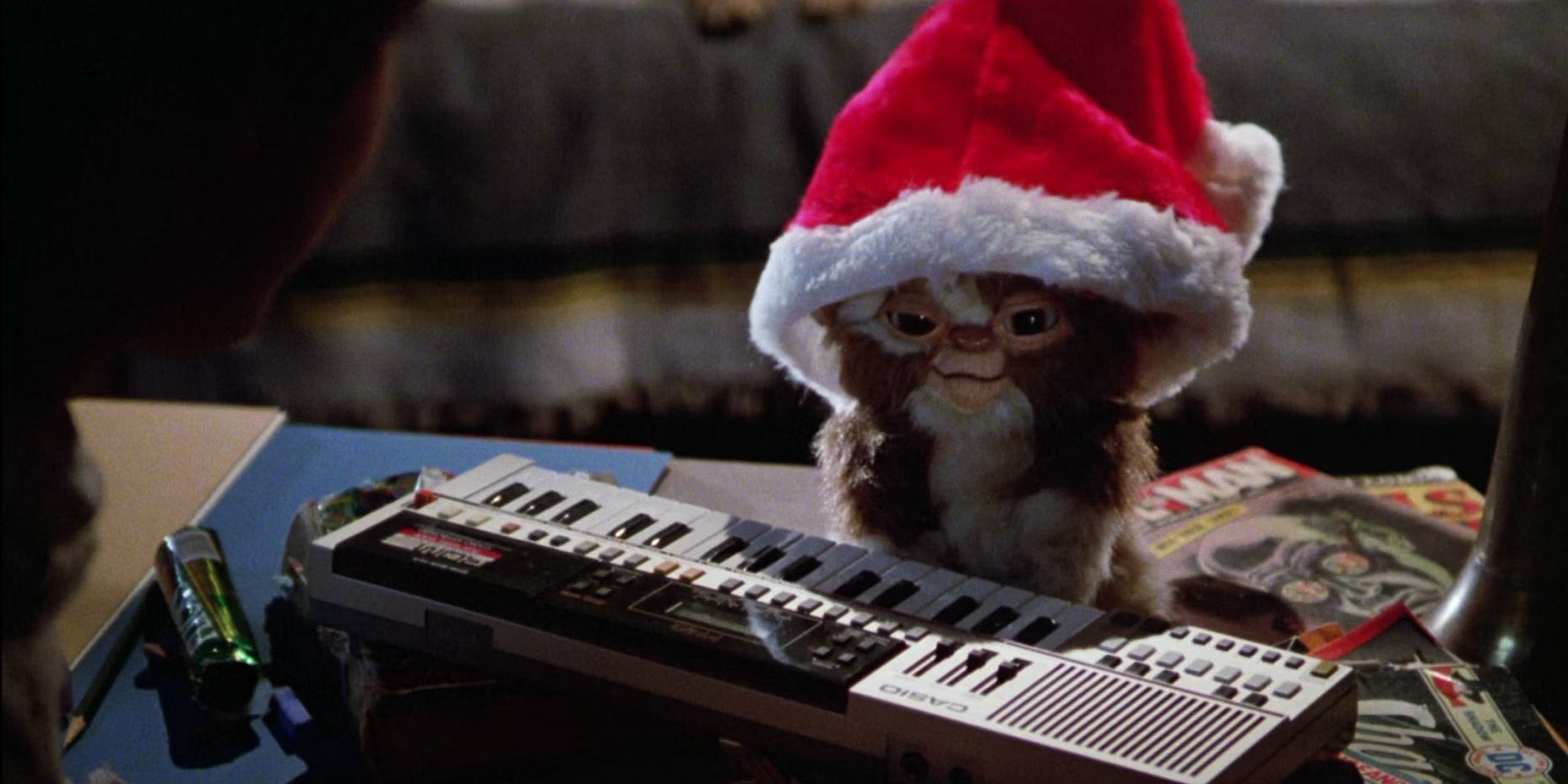 Gizmo en Gremlins con un gorro de Papá Noel sentado al lado de un teclado.