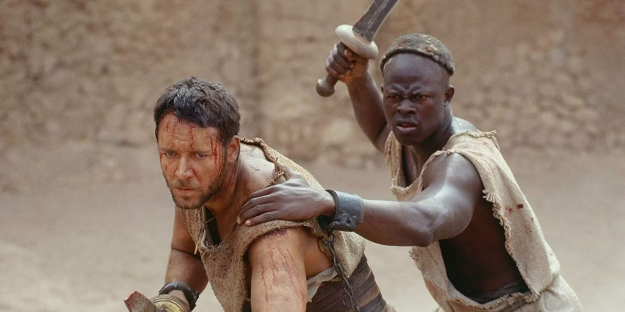 Russell Crowe y Djimon Hounsou sosteniendo espadas y preparándose para una pelea en Gladiator.