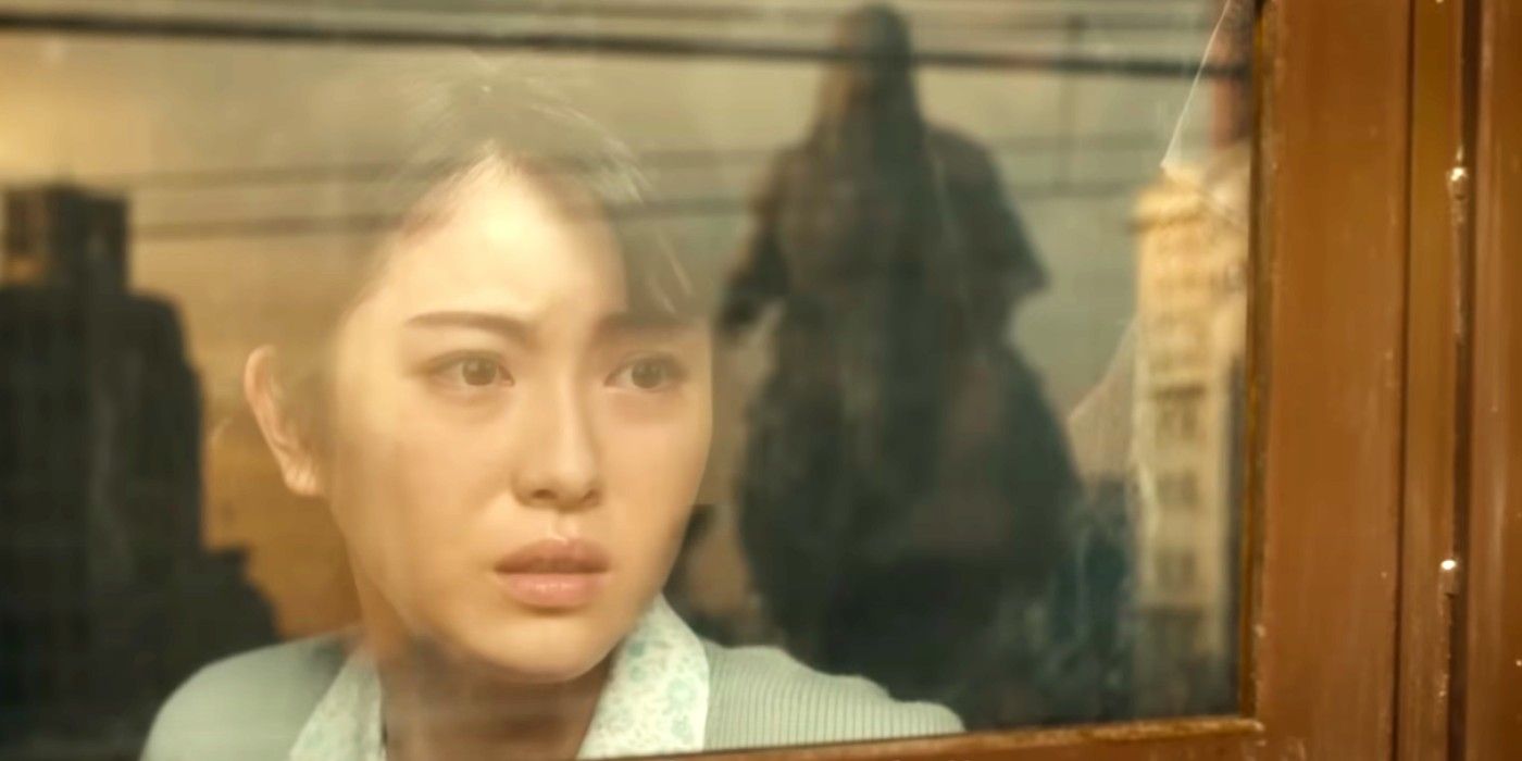 A woman looking out a window at Godzilla in Godzilla Minus One