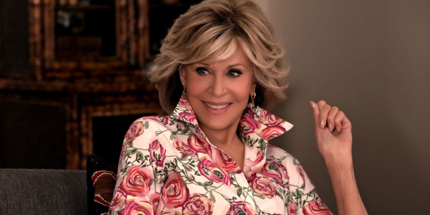 Grace (Jane Fonda) in a floral blouse, sitting and smiling in Grace and Frankie