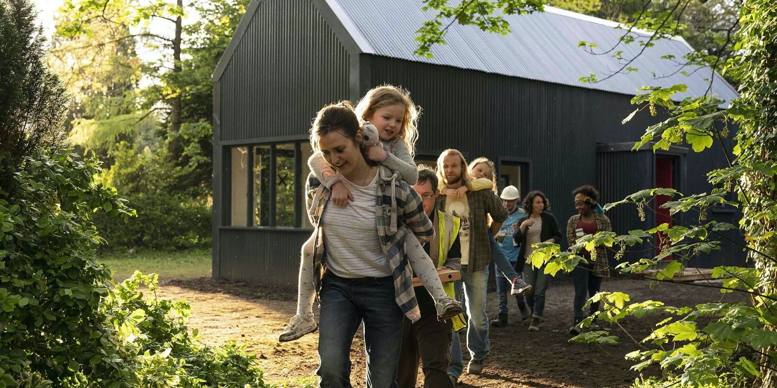 A group of people following a mother holding her child in Herself