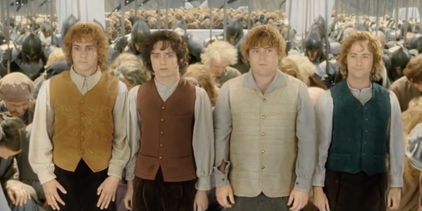 Merry, Frodo, Sam, and Pippin standing as the royal court bows to them in the ending of The Lord of the Rings.