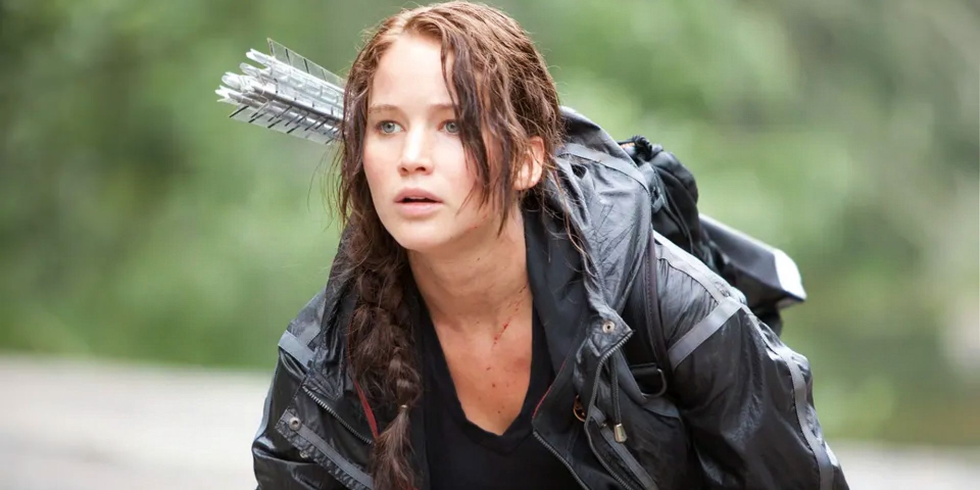 Katniss is kneeling on the ground, with arrows on her back in The Hunger Games.