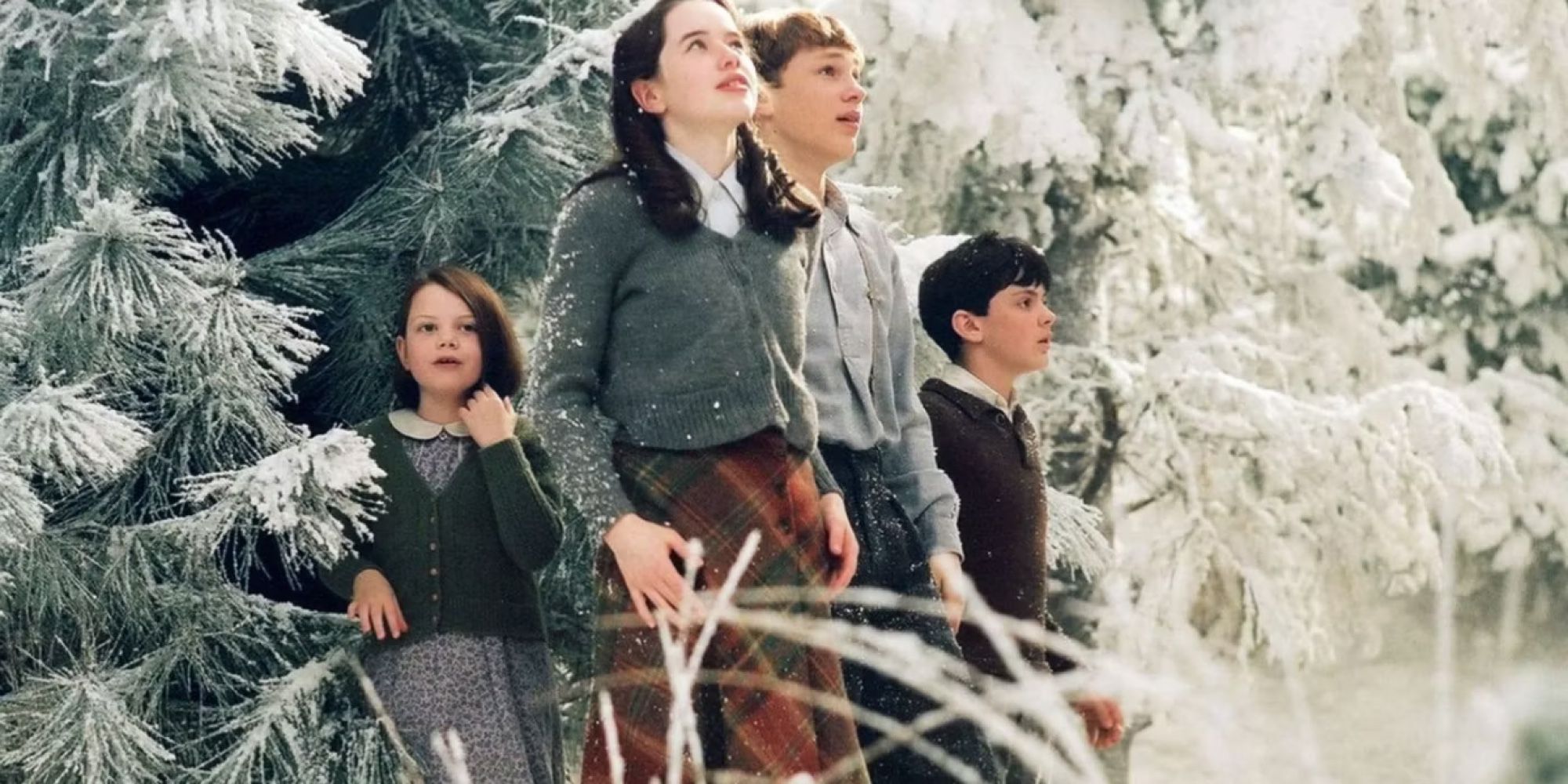 Lucy, Susan, Peter, and Edmund walk out of the trees in The Chronicles of Narnia. 