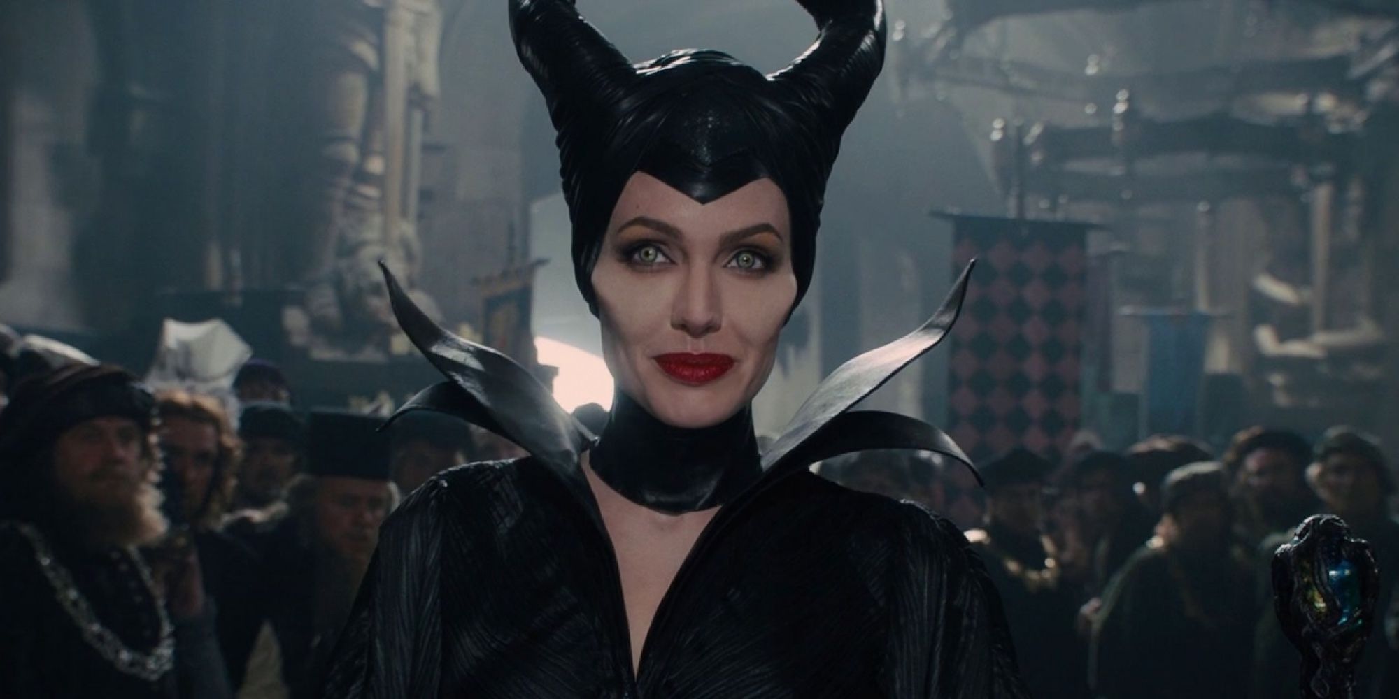 Maleficent smiles, as she walks through a crowd of people. 