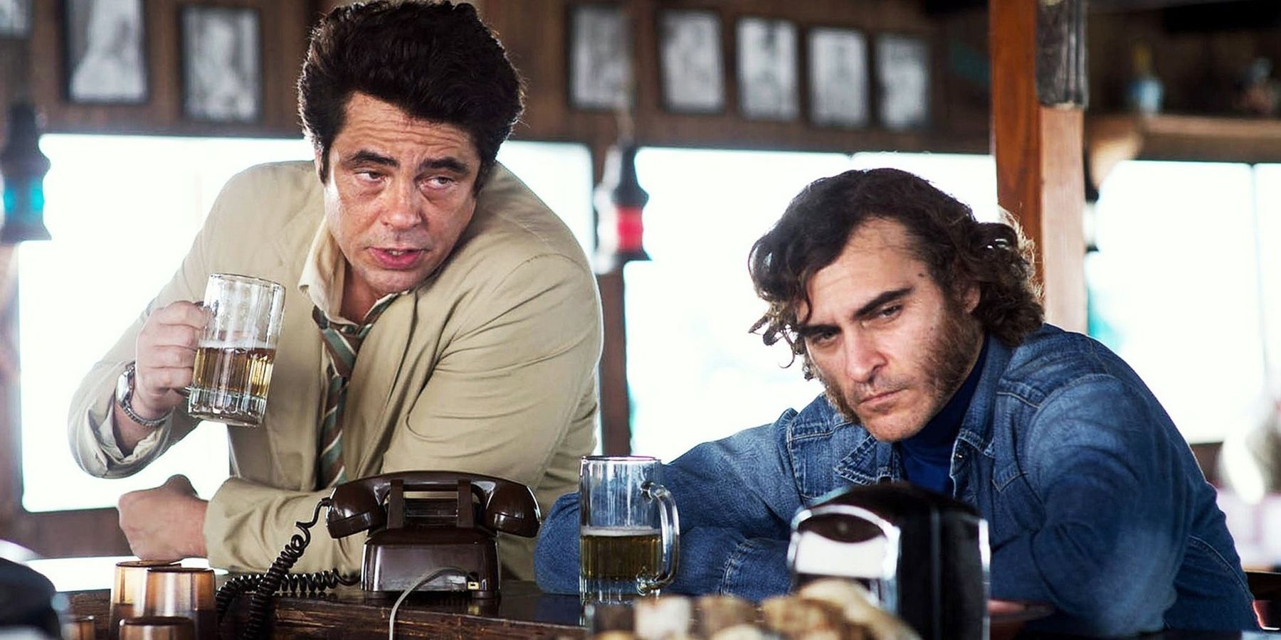 Doc (Joaquin Phoenix) and Sauncho (Benicio del Toro) drinking at a bar in Inherent Vice