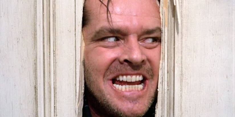 Jack Nicholson como Jack enfiando a cabeça através de um buraco na porta no brilho
