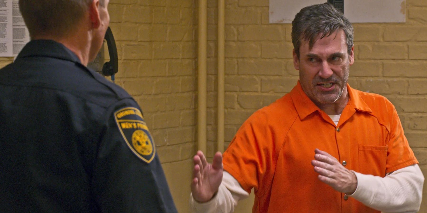 Jon Hamm in a prison jumpsuit preparing to fight a guard in Unbreakable Kimmy Schimdt