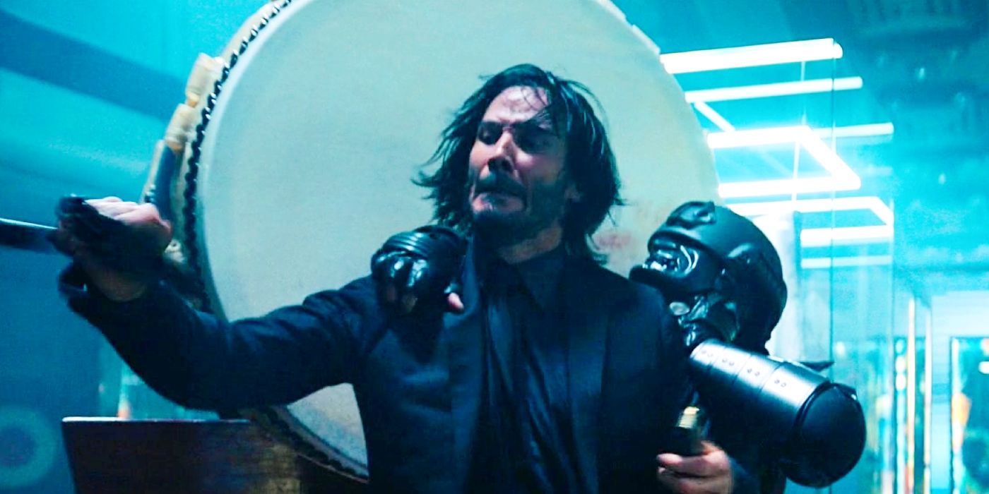 Keanu Reeves as John Wick reloading a pistol while fighting a masked enemy in John Wick: Chapter 4.
