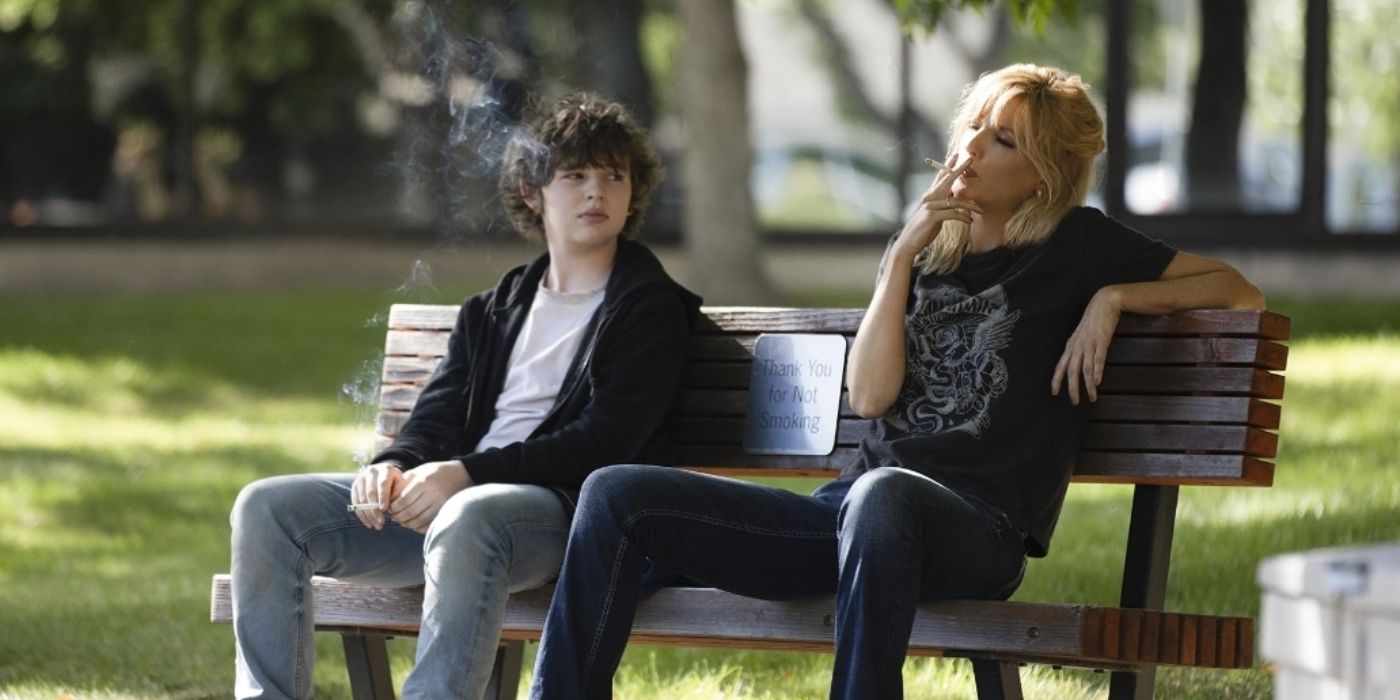 Beth Dutton (Kelly Reilly) and Carter (Finn Little) smoking cigarettes while sat on a bench in Yellowstone.