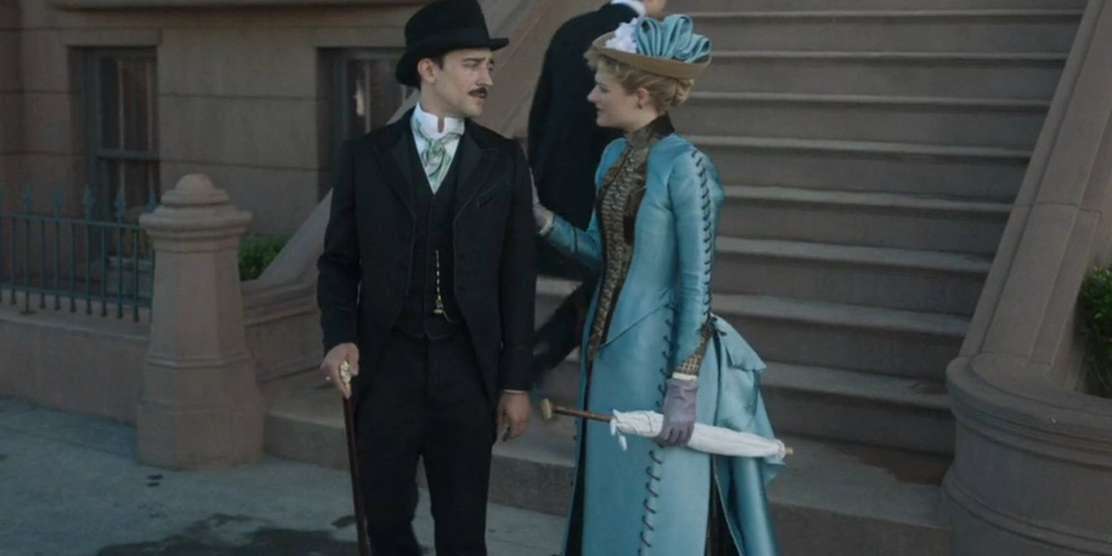 Louisa Jacobson as Marian holding onto Oscar's (Blake Ritson) shoulder in The Gilded Age.
