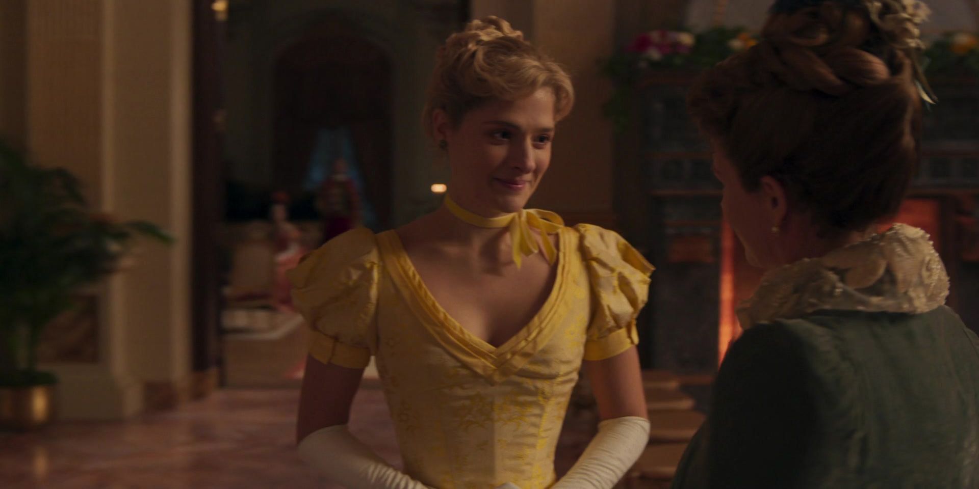 Marion in a yellow dress smiling in The Gilded Age.