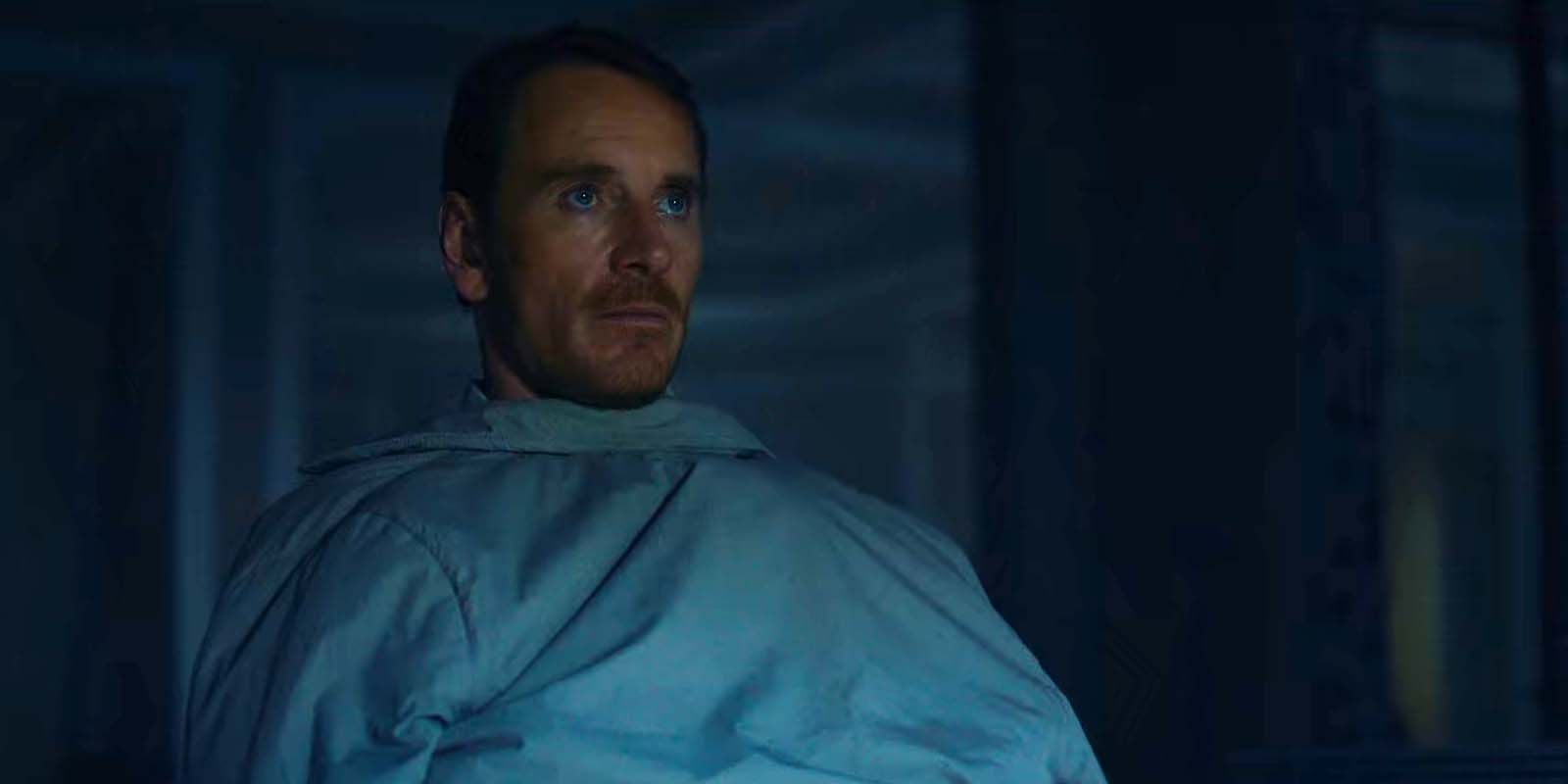 Michael Fassbender using his jacket as a blanket as the killer in The Killer