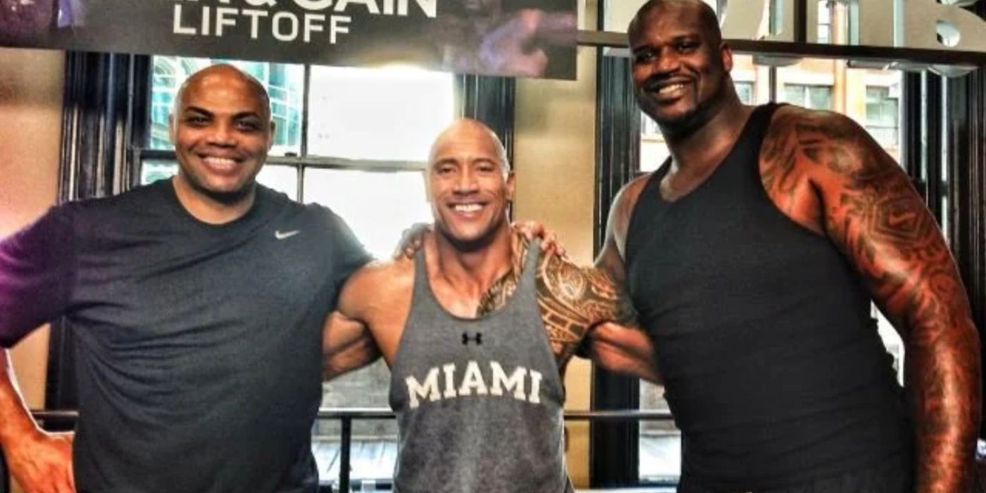 Dwayne Johnson stands next to Shaq and Charles Barkley in a gym