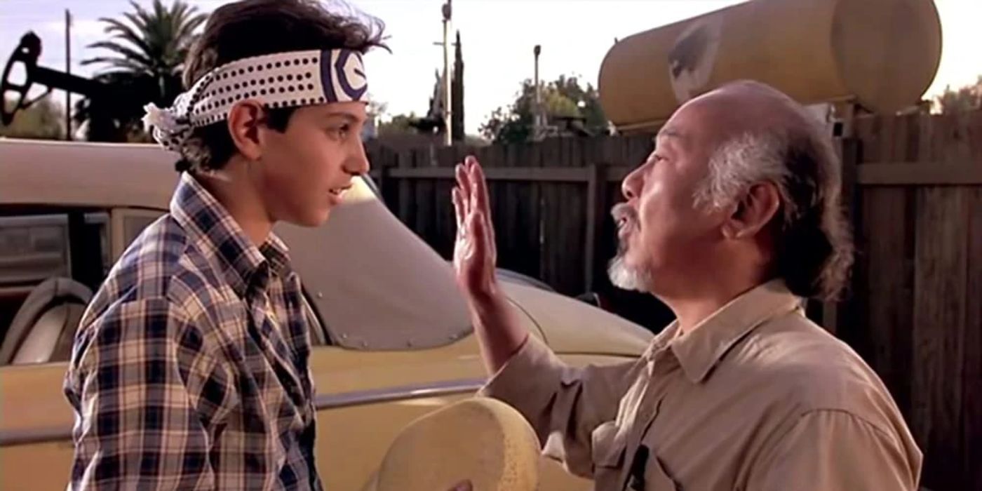Mr. Miyagi talking to Daniel in front of a car in The Karate Kid
