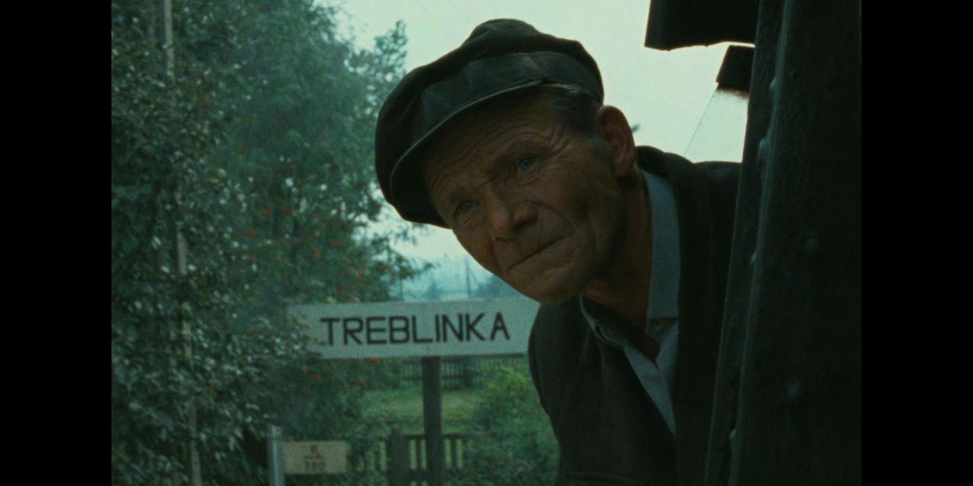 A man sticks his head out of a train car in front of the Treblinka sign in Shoah-1985