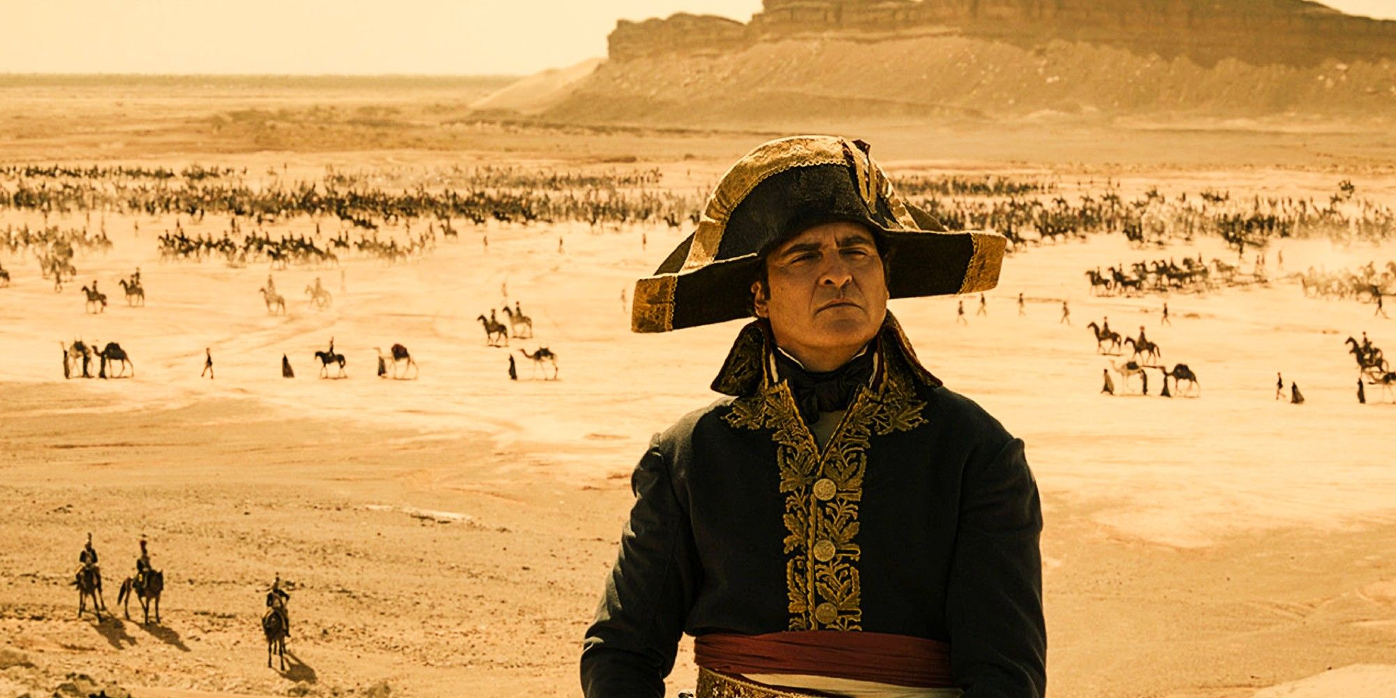 Joaquin Phoenix as Napoleon standing over a battlefield