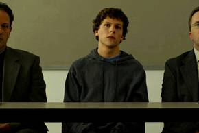 Jesse Eisenberg as Mark Zuckerberg standing next to two lawyers in the Social Network