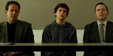 Jesse Eisenberg as Mark Zuckerberg standing next to two lawyers in the Social Network