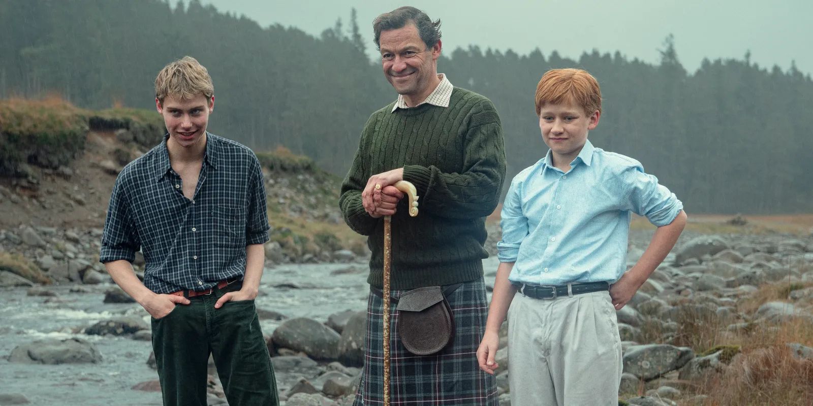 Charles (Dominic West), Harry (Flynn Edwards) y William (Rufus Campa) están junto al río en la temporada 6 de The Crown.